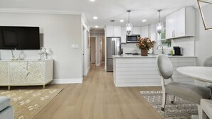 Une cuisine moderne avec des meubles blancs, un îlot central et des luminaires suspendus.