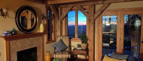 A cozy living room with a fireplace, a sofa, a coffee table, and a view of the outdoors.