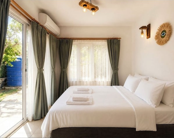 A hotel room with a bed, curtains, an air conditioning unit, a wall-mounted light fixture, and a decorative wall piece. - YAKAMOZ BEACH (Marmaris)