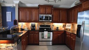 A kitchen with wooden cabinets, a stainless steel refrigerator, a microwave, an oven, and a coffee maker. - 4 Bedroom Modern Pool home close to UCF (Oviedo)