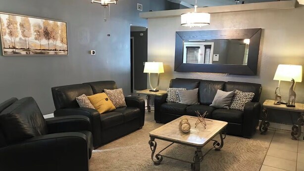 A living room with two black leather sofas, a coffee table, and two lamps. - 4 Bedroom Modern Pool home close to UCF (Oviedo)