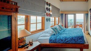 A bedroom with a bed, a TV, a window, and a view of the sea. - Kampung Kecil Front Beach  (Kubu)