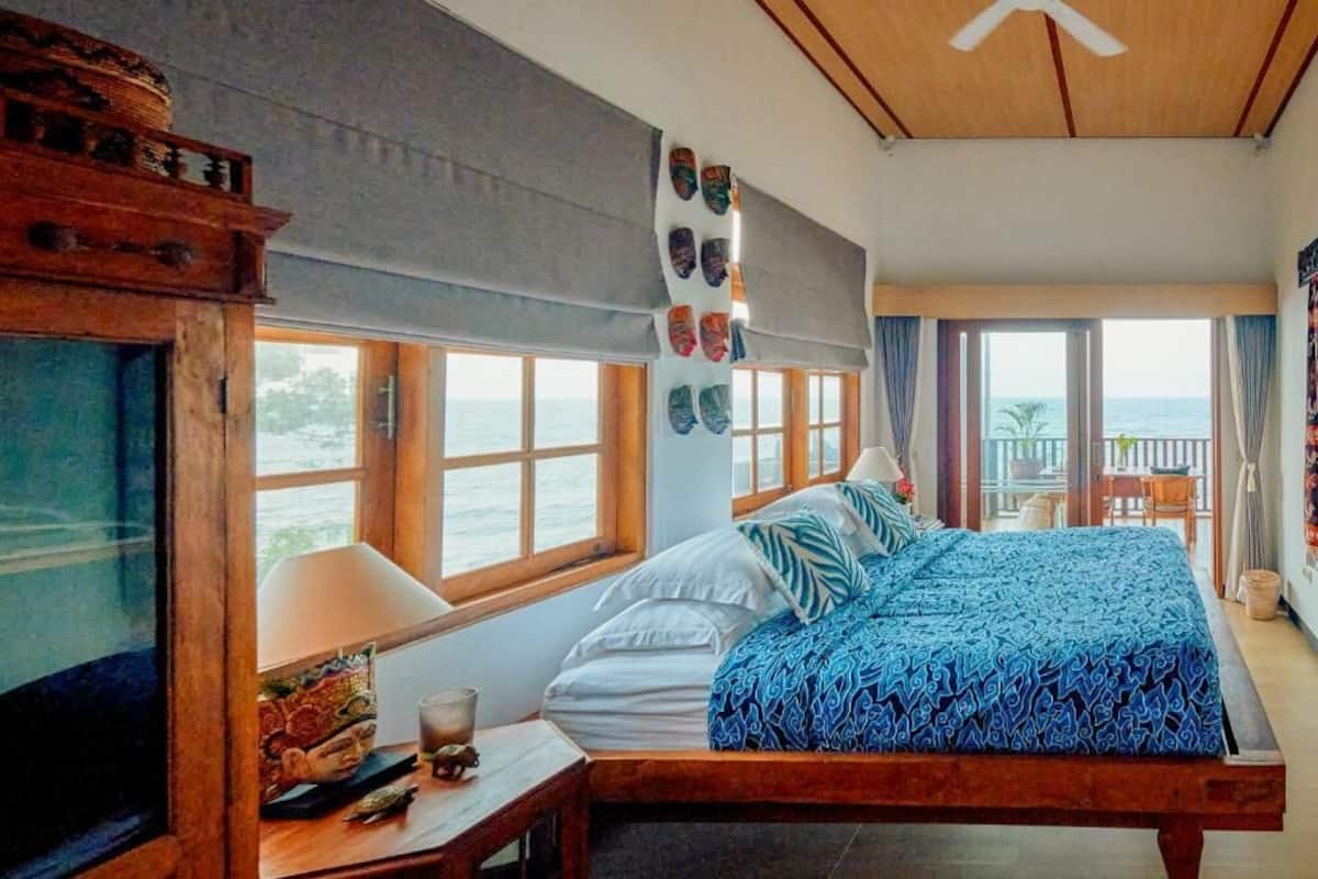 A bedroom with a bed, a TV, a window, and a view of the sea.
