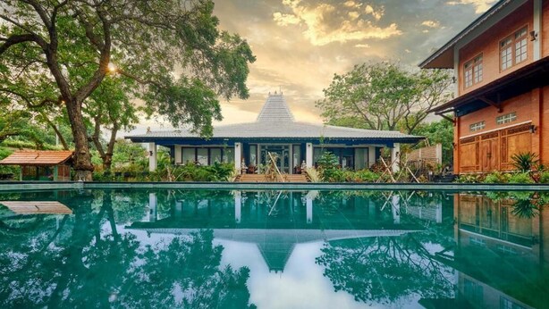 A serene pool area with a traditional building in the background. - Kampung Kecil Front Beach  (Kubu)