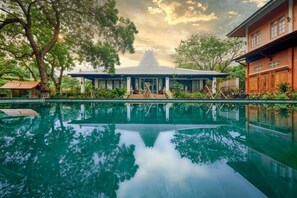 A serene pool area with a traditional building in the background. - Kampung Kecil Front Beach  (Kubu)