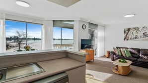 Ein modernes Wohnzimmer mit Seeblick, eine Küchenzeile inklusive Backofen und eine Sitzecke mit einer Ledersofa.