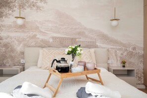 A bedroom with a bed, a tray with a kettle, cups, and flowers, and a mural of a landscape. - Downtown Apt - Parking, Balcony, Top Location - by Rentujemy (Łódź)