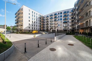 A modern apartment complex with multiple balconies, a paved walkway, and a yellow van parked in the lot. - Downtown Apt - Parking, Balcony, Top Location - by Rentujemy (Łódź)