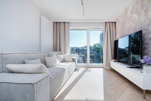 Una sala de estar moderna con un sofá, un televisor de pantalla plana y un balcón con vista a la ciudad.