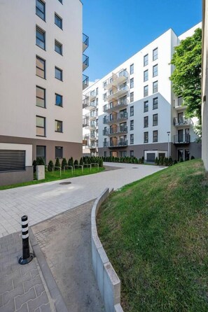 Un complejo de apartamentos moderno con varios pisos, balcones y un patio ajardinado.
