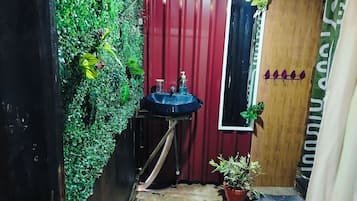 Pieni kylpyhuone, jossa on pesuallas, peili ja ruukussa oleva kasvi.