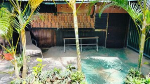 A courtyard with a bench, palm trees, and a brick wall. - Celestial forest (Provincia de Alajuela)