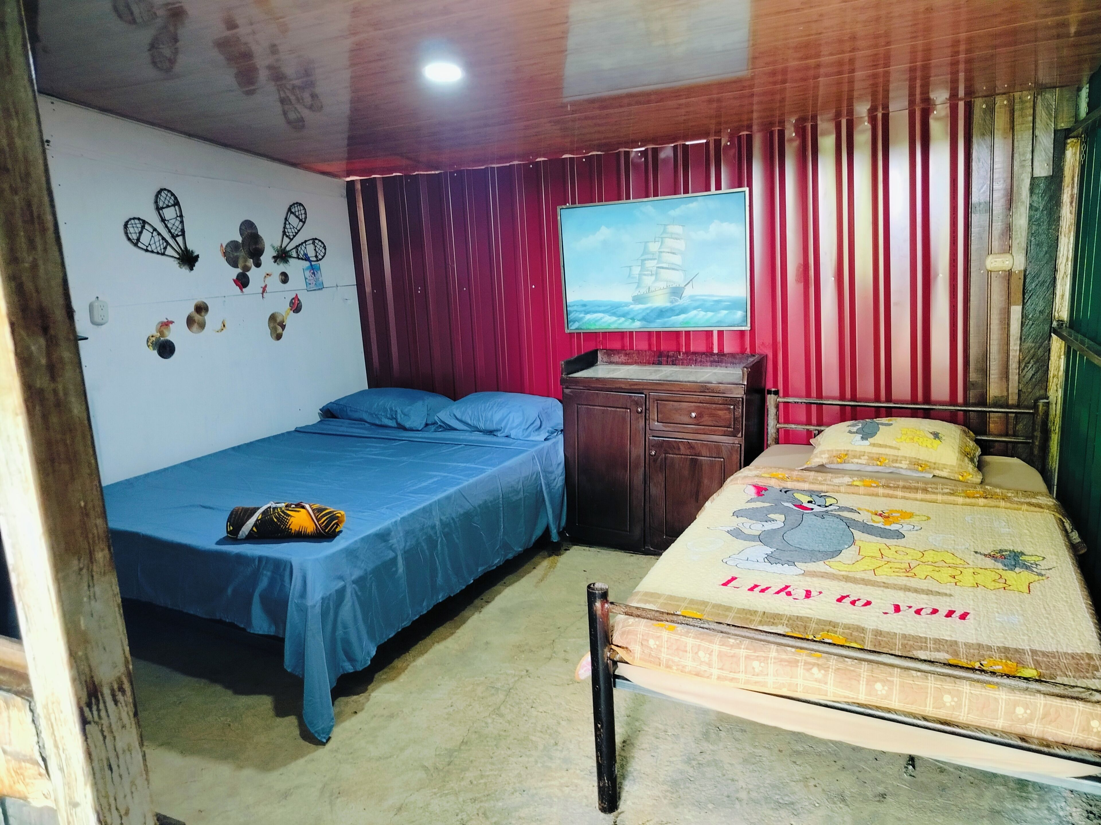 A bedroom with two beds, a wooden dresser, a wall-mounted TV, and decorative wall art.