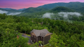 A house surrounded by dense forest with a mountain backdrop. - Pool Cabin with 5 King Bedrooms (Cosby)