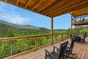 A wooden deck with outdoor furniture overlooking a forested mountain landscape. - Pool Cabin with 5 King Bedrooms (Cosby)