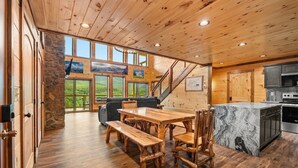 Un interior de madera con comedor, cocina y ventanas amplias.