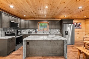 Eine moderne Küche mit Granit Arbeitsplatten, Edelstahlgeräten und Holzbalkendecke.