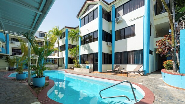 A swimming pool with a red border, surrounded by potted plants and lounge chairs. - Central One Bedroom Apartment on Third Floor (Sosúa)