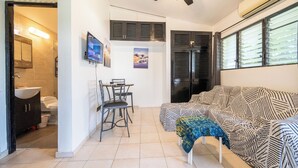 A compact living space with a kitchenette, a dining area, a sofa, and a ceiling fan. - Central One Bedroom Apartment on Third Floor (Sosúa)
