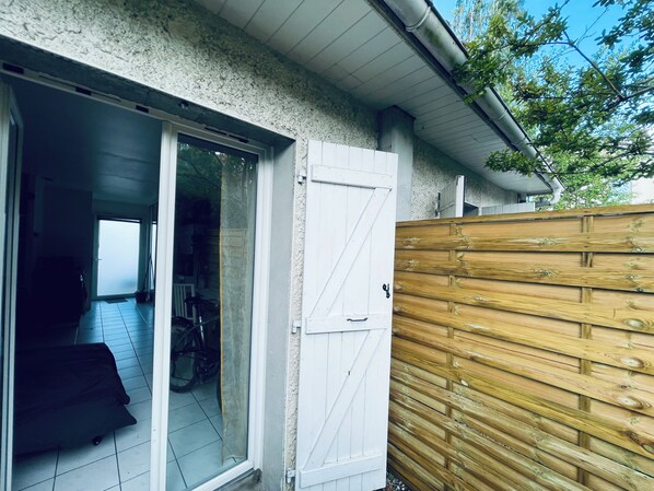 A residential entrance with a sliding glass door, a wooden fence, and a tiled floor.