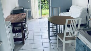 Ett kompakt kök med en matplats, en skjutdörr i glas som leder ut till en trädgård och en vit soffa.