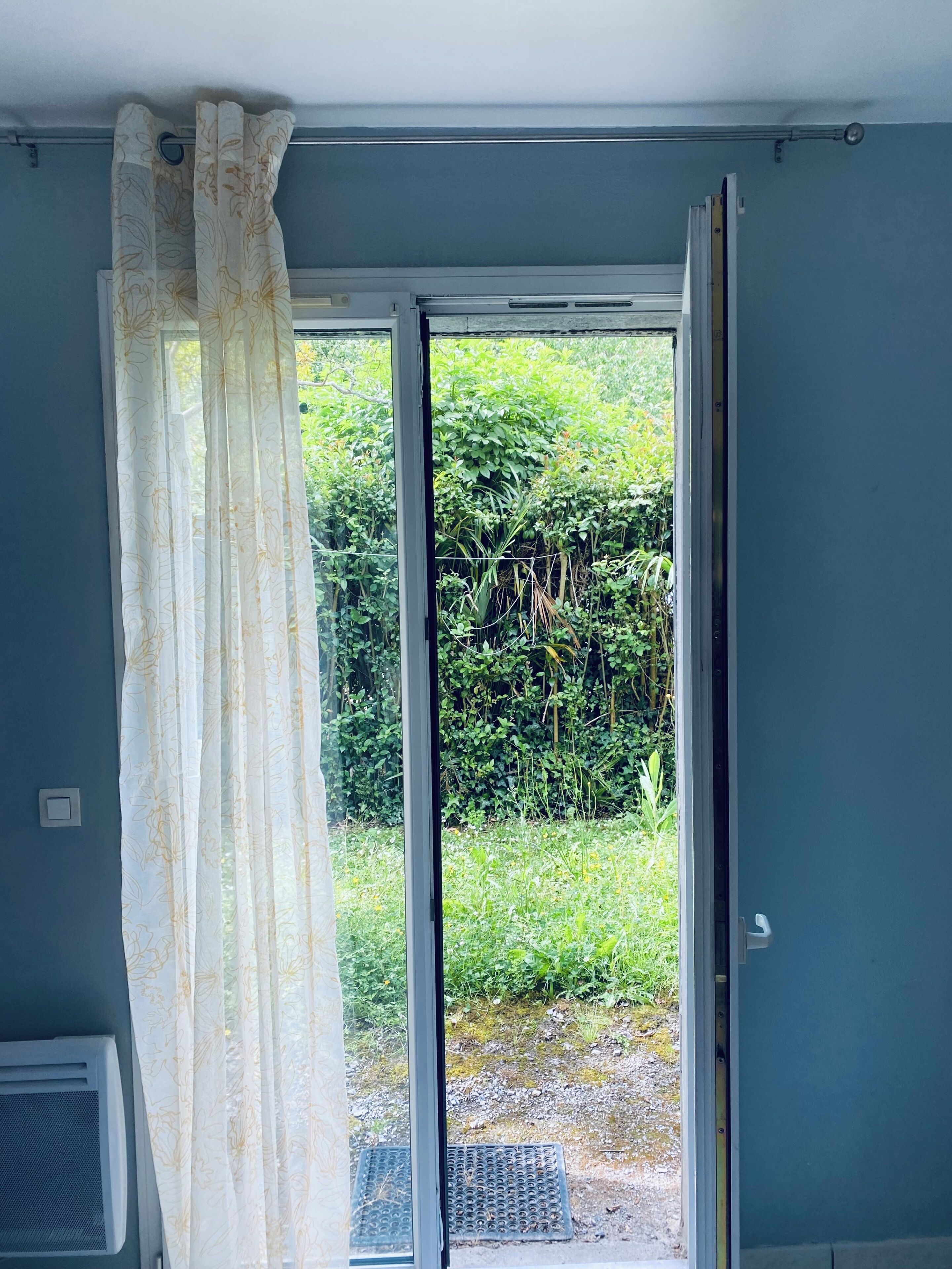 Una habitación con puerta corrediza de vidrio que da a un jardín.