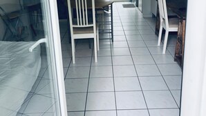 Ett rum med en säng, ett matbord med stolar, ett litet kök och ett stort fönster.