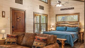 A rustic cabin interior with a bed, wooden walls, a ceiling fan, and a sign indicating the Appalachian Trail.