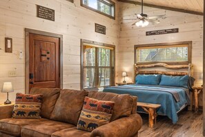 Ein rustikales Ferienhaus-Interieur mit einem Bett, Holzwänden, einem Deckenventilator und einem Schild, das auf den Appalachian Trail hinweist.