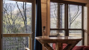 A room with a view of trees through a window, a wooden table, and a chair. - Gatlinburg 23 min + Hot Tub + Fire Pit #1 (Cosby)