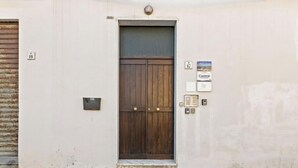 A building with a large wooden door, a small window, and a sign that reads 'Carmè'. - Camera chiara 3 – Relax with a View in the Heart of Alghero 🌊✨ (Alghero)