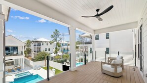 A modern outdoor deck with a pool, lounge chairs, and a ceiling fan. - Retreat with Pool, LSV, Peloton and More (Santa Rosa Beach)