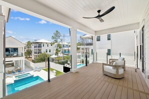Eine moderne Außenterrasse mit Pool, Liegestühlen und Deckenventilator.