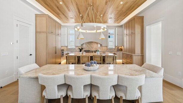 A spacious kitchen with a large island, wooden cabinets, and a modern chandelier. - Retreat with Pool, LSV, Peloton and More (Santa Rosa Beach)