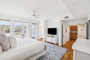 Ein Schlafzimmer mit einem Bett, einem Fernseher, einem Deckenventilator und Blick ins Freie.