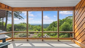 Una terraza de madera con amplios ventanales que dan a un paisaje boscoso.