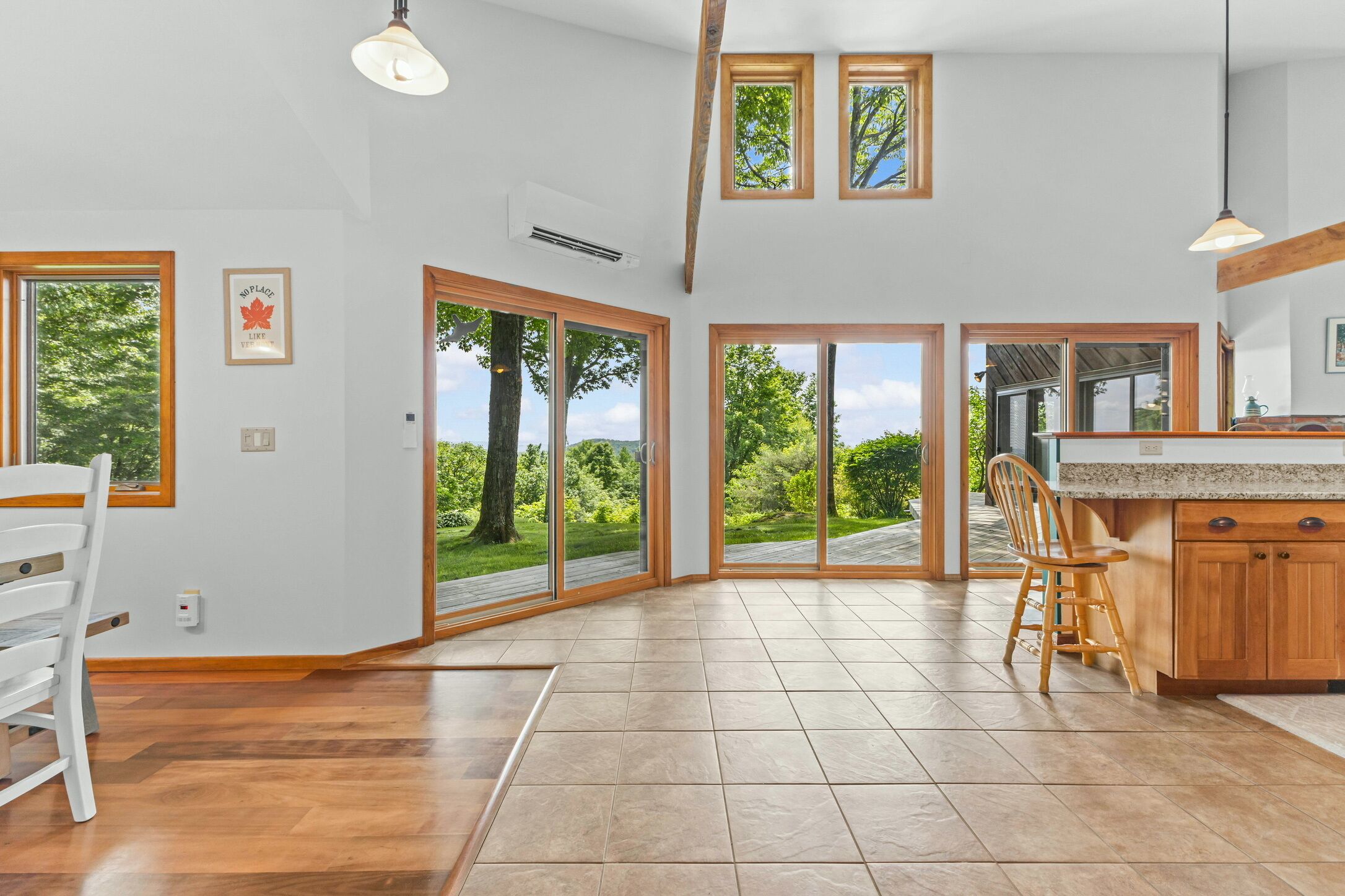 A spacious kitchen with large windows, wooden flooring, and a view of the outdoors.