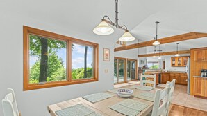 Un comedor amplio con una gran mesa de madera, varias sillas y vistas al exterior a través de amplios ventanales.
