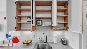 Cozinha moderna com pia de aço inoxidável, uma tigela de frutas, torradeira e armários de madeira.