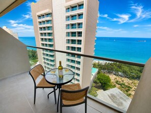A balcony with a table, two chairs, and a bottle of wine. - Apartamentos Reserva-Bellohorizonte SOHO (Bello Horizonte)