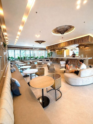 Ein moderner Loungebereich mit Sitzgelegenheiten, Tischen und einer Bar.