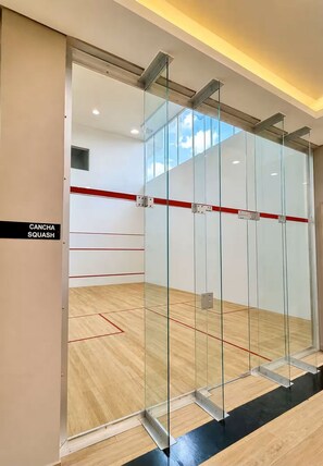 Ein Squashplatz mit Glaswänden, Holzboden und einer roten Linie zur Markierung des Spielfelds.