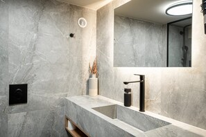 A modern bathroom with a marble wall, a sink with a black faucet, and a mirror. - Noemi City Loft 2, Loft (Iraklio)