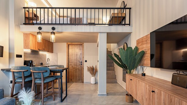 Une cuisine moderne avec un coin repas, un escalier et un salon équipé d’un téléviseur.