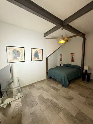 Ein Schlafzimmer mit einem Bett, einem Schreibtisch und zwei gerahmten Bildern an der Wand.
