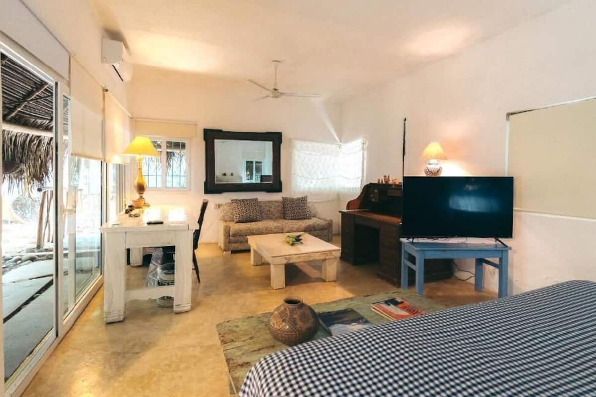 Um espaço compacto com sofá, mesa de centro, televisão e uma pequena área de refeições.