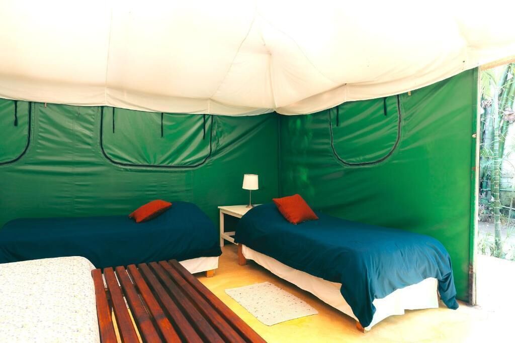 A tented room with two beds, a small table, and a window.