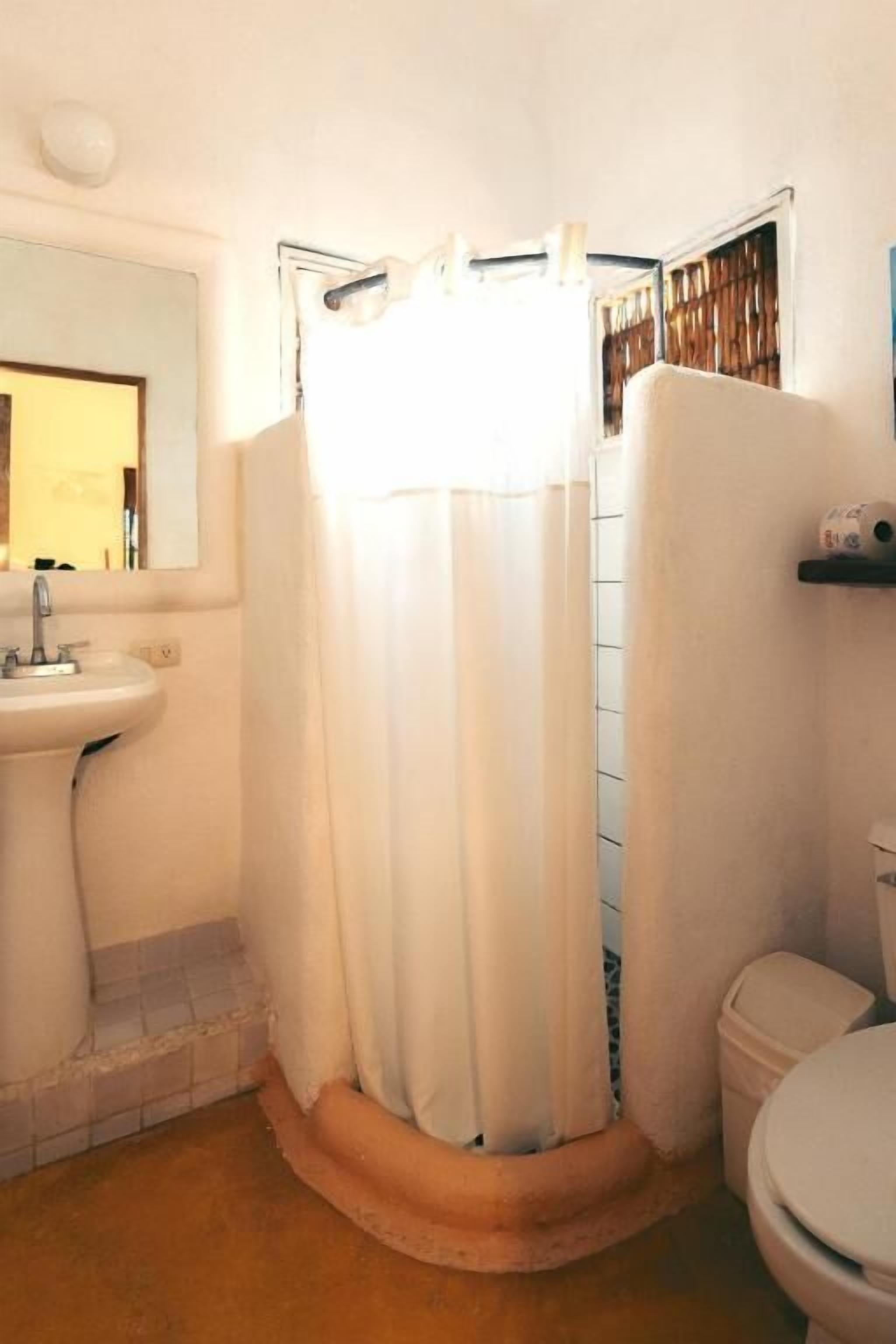 A bathroom with a shower curtain, a sink, and a toilet.