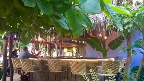 Zona de bar al aire libre con sillas de mimbre y una barra.