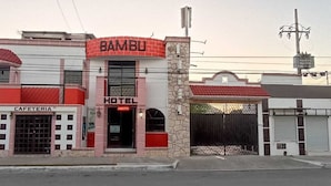 Un edificio con un letrero que dice 'BAMBU', un letrero que indica 'HOTEL' y un letrero que anuncia 'CAFETERIA'.